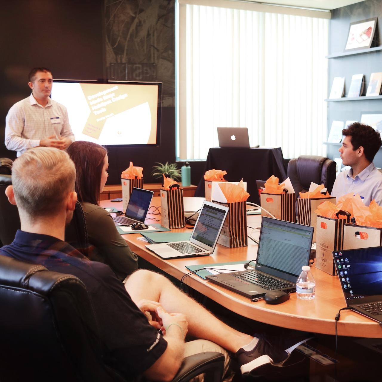 man standing in front of people sitting beside table with laptop computers